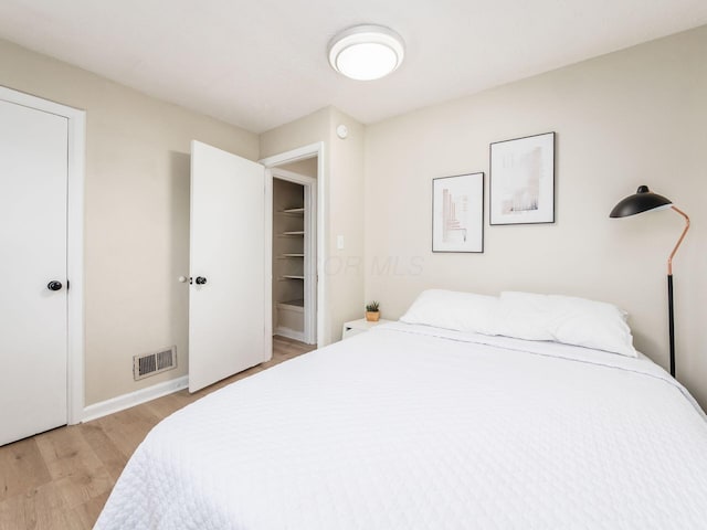 bedroom featuring light wood-style flooring, visible vents, and baseboards