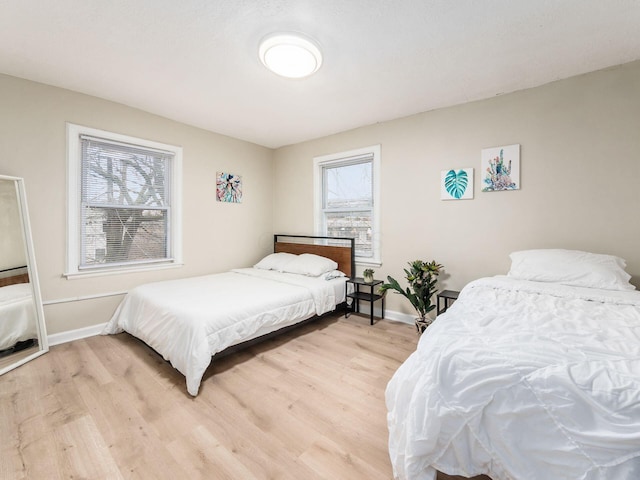 bedroom featuring light wood finished floors and baseboards