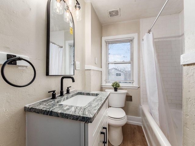 bathroom with visible vents, a textured wall, toilet, vanity, and wood finished floors