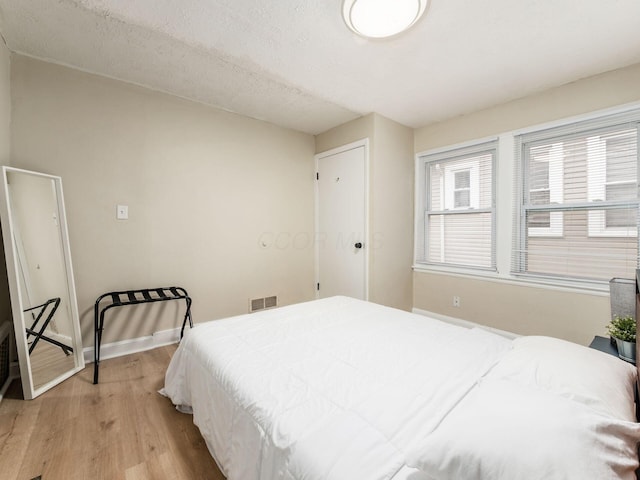 bedroom featuring wood finished floors, visible vents, and baseboards