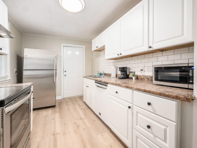 kitchen with stainless steel appliances, white cabinetry, light wood-style flooring, and backsplash