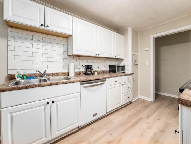 kitchen featuring stainless steel microwave, light wood-style floors, white cabinetry, white dishwasher, and a sink