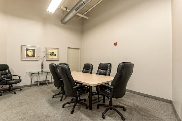 carpeted home office featuring visible vents, a towering ceiling, and baseboards