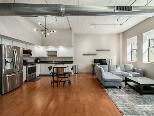 kitchen featuring stainless steel appliances, tasteful backsplash, visible vents, open floor plan, and white cabinets