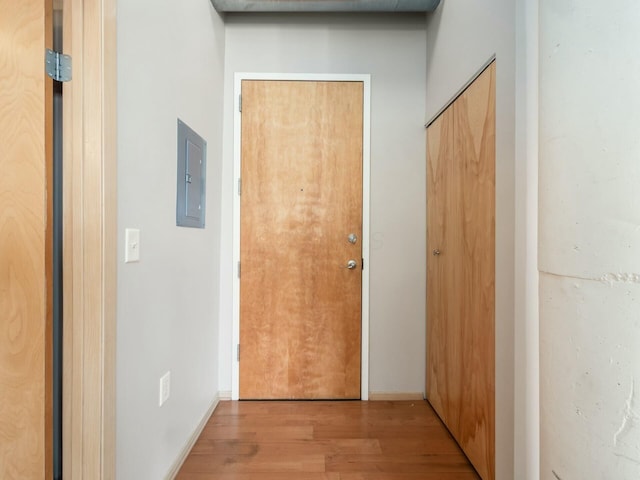 corridor featuring wood finished floors, electric panel, and baseboards