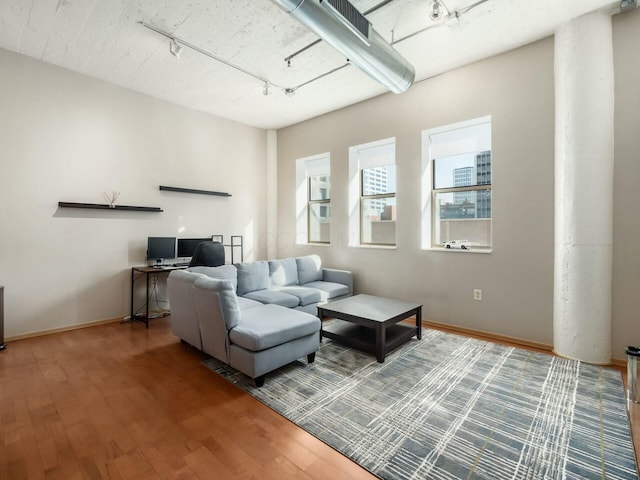 living area featuring track lighting, baseboards, and wood finished floors