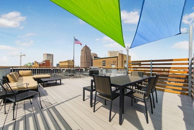 deck with a view of city, outdoor dining area, and grilling area