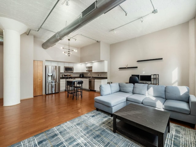 living room featuring a towering ceiling, visible vents, dark wood finished floors, and track lighting