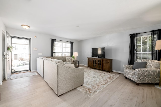 living room with light wood-type flooring, plenty of natural light, and baseboards