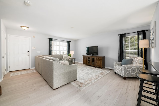 living area with light wood-style flooring, baseboards, and a wealth of natural light