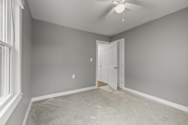 carpeted empty room featuring baseboards, visible vents, and a ceiling fan