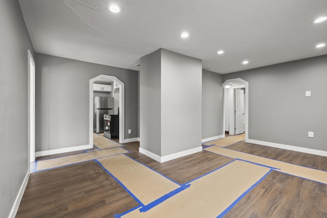 workout room featuring arched walkways, wood finished floors, baseboards, and recessed lighting