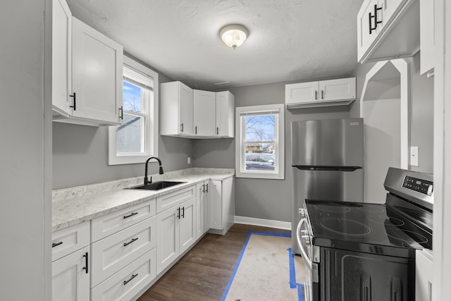 kitchen with baseboards, white cabinets, dark wood-type flooring, stainless steel appliances, and a sink