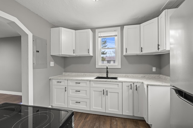 kitchen with black electric range oven, freestanding refrigerator, white cabinetry, a sink, and electric panel