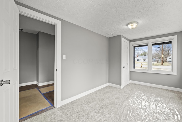 spare room featuring baseboards, a textured ceiling, and carpet flooring