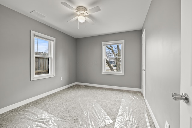 carpeted spare room featuring a ceiling fan, visible vents, and baseboards