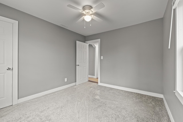 carpeted spare room featuring visible vents, baseboards, and a ceiling fan