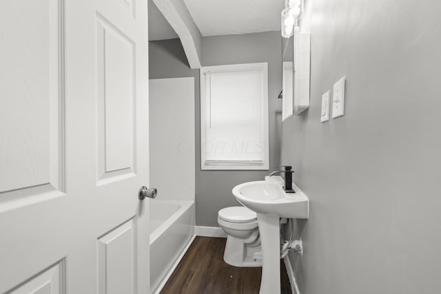 bathroom with a washtub, baseboards, toilet, and wood finished floors