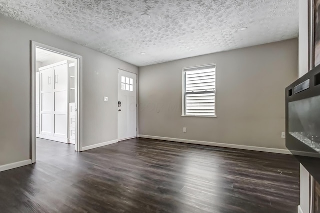 interior space featuring baseboards, dark wood-type flooring, and a textured ceiling