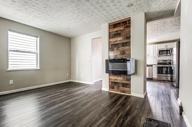 unfurnished living room with a textured ceiling, dark wood finished floors, visible vents, and baseboards