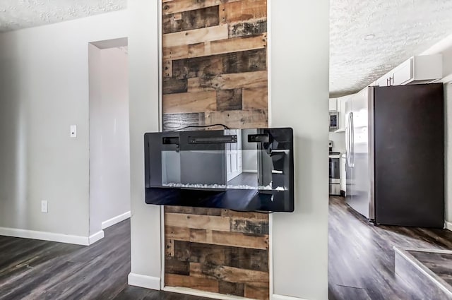 kitchen featuring appliances with stainless steel finishes, white cabinetry, a textured ceiling, wood finished floors, and baseboards