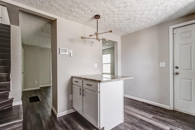 kitchen featuring dark wood finished floors, a textured ceiling, baseboards, and light stone countertops