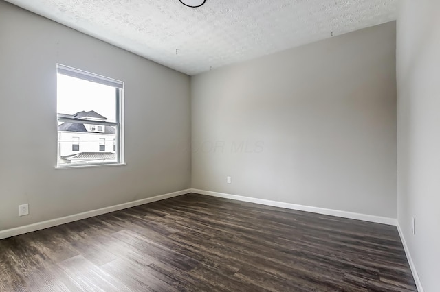 unfurnished room with a textured ceiling, dark wood finished floors, and baseboards