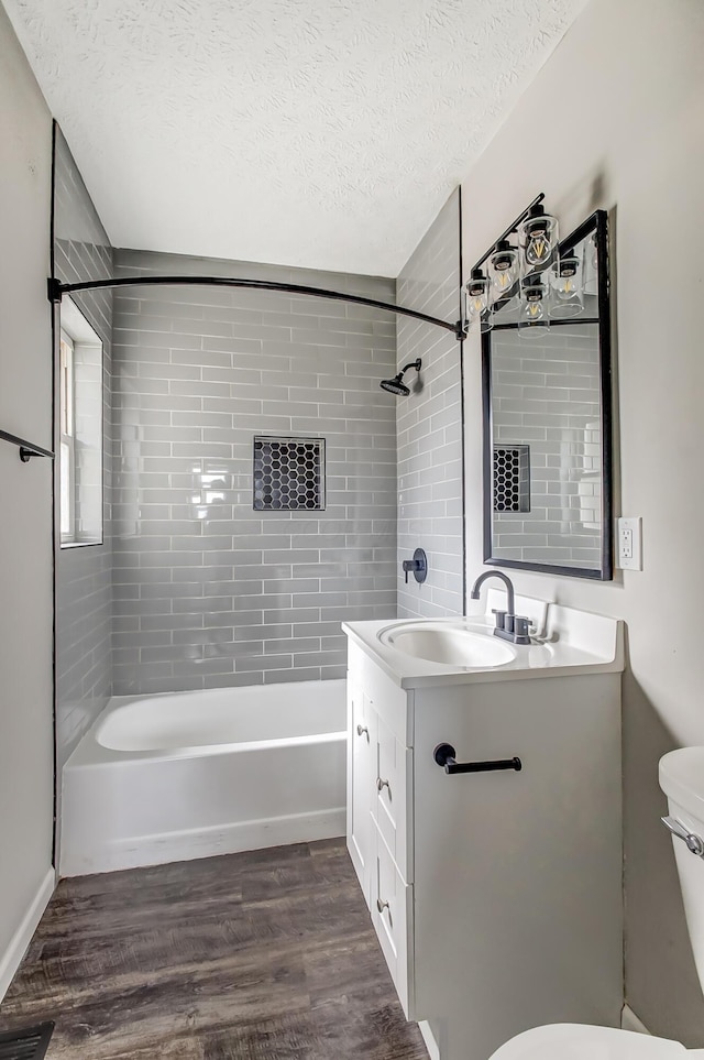 full bathroom featuring  shower combination, a textured ceiling, toilet, and wood finished floors