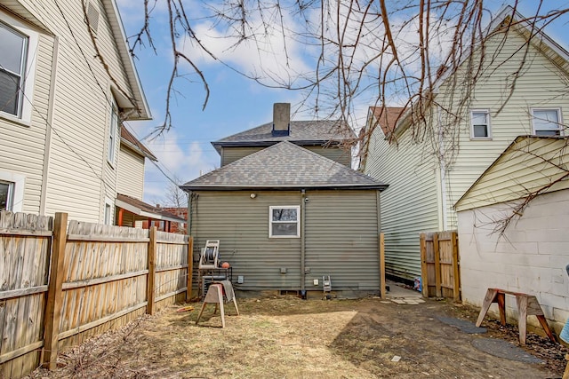 back of property featuring a shingled roof and fence