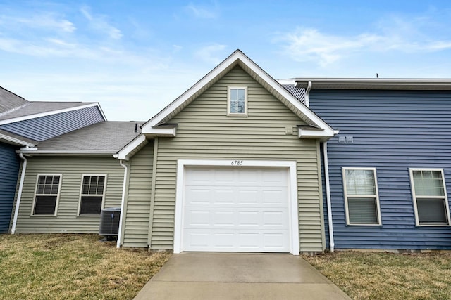 view of front of house featuring a front yard, concrete driveway, an attached garage, and central air condition unit