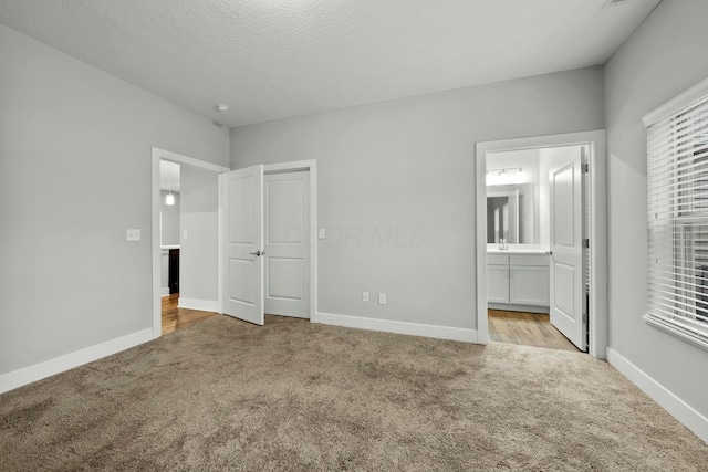 unfurnished bedroom with carpet, ensuite bath, and baseboards