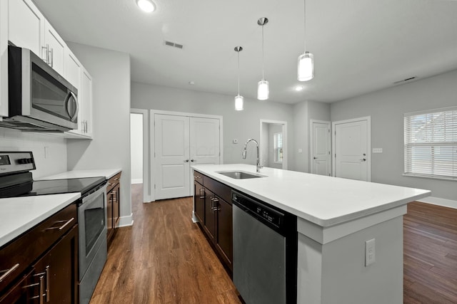 kitchen with appliances with stainless steel finishes, visible vents, a sink, and dark wood-type flooring