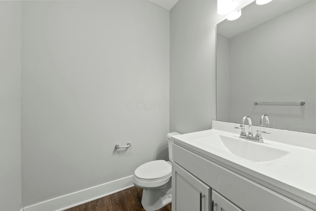 bathroom with baseboards, vanity, toilet, and wood finished floors