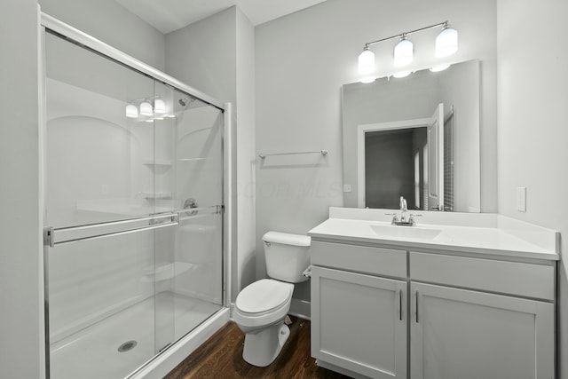 full bath with a stall shower, vanity, toilet, and wood finished floors