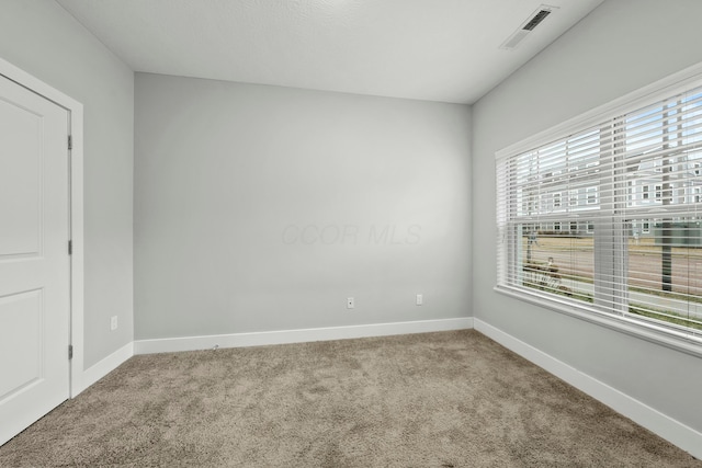 spare room featuring carpet flooring, visible vents, and baseboards