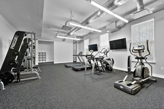 workout area featuring a textured ceiling and baseboards