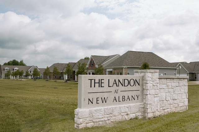 community / neighborhood sign featuring a lawn and a residential view