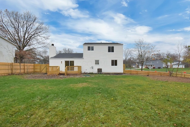 rear view of house with a chimney, fence, a lawn, and a wooden deck