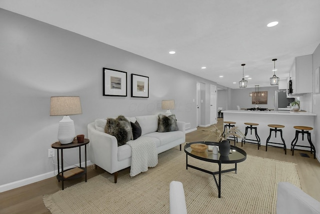 living area with light wood-style floors, visible vents, baseboards, and recessed lighting