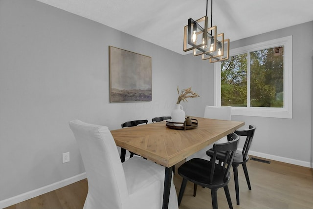 dining room featuring light wood-type flooring, visible vents, and baseboards