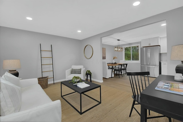 living room featuring baseboards, an inviting chandelier, light wood-style flooring, and recessed lighting