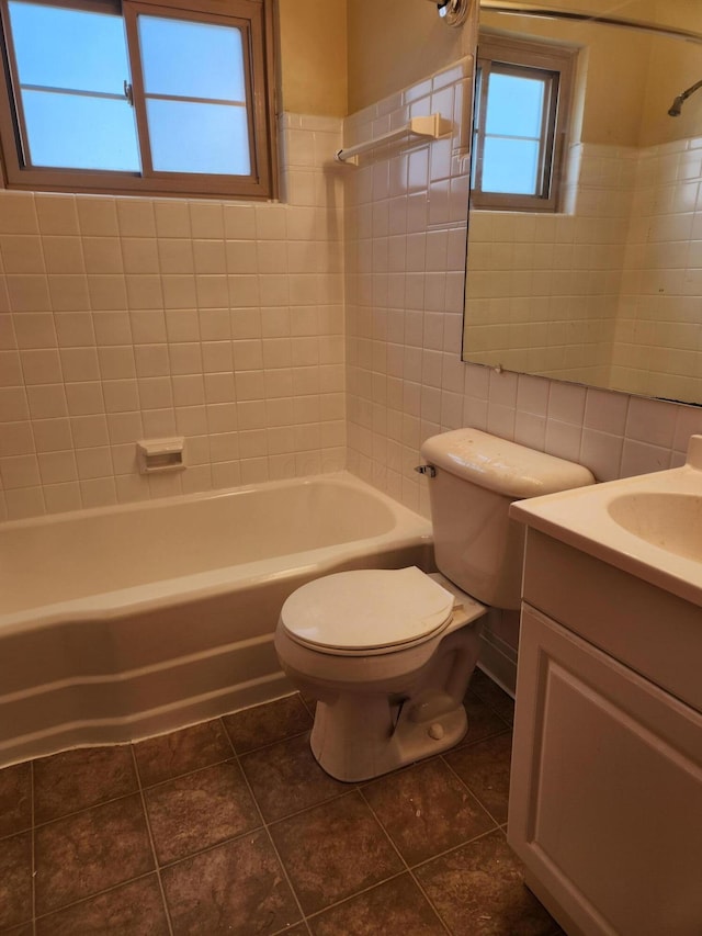 full bath featuring bathing tub / shower combination, toilet, tile patterned flooring, vanity, and tile walls