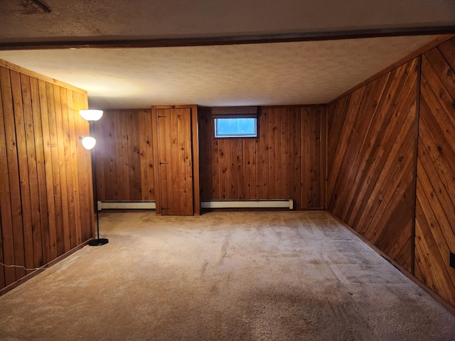 basement with a baseboard heating unit, wood walls, a textured ceiling, and carpet