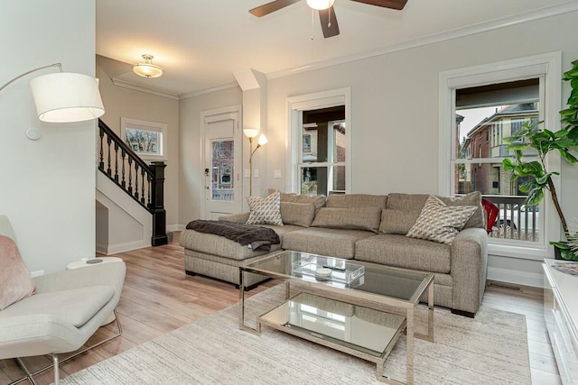 living area with light wood finished floors, stairs, a wealth of natural light, and crown molding