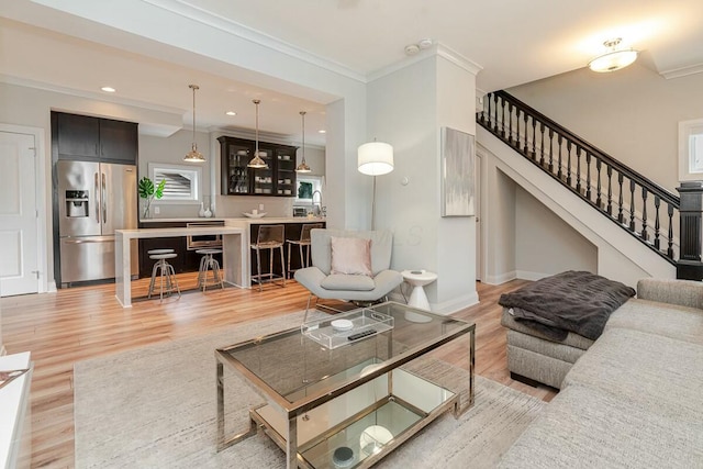 living area featuring recessed lighting, baseboards, stairs, ornamental molding, and light wood-type flooring