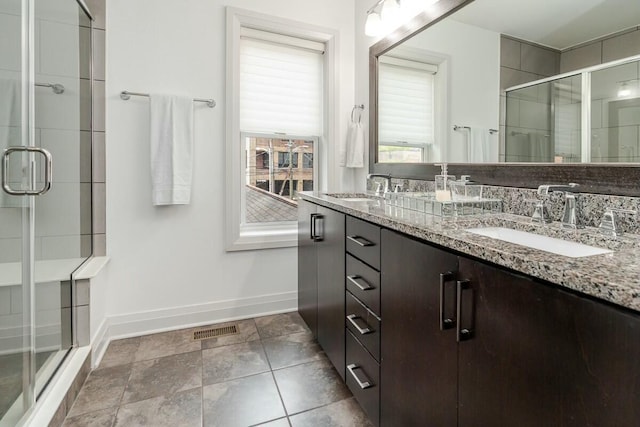 full bath with double vanity, a stall shower, a sink, and visible vents