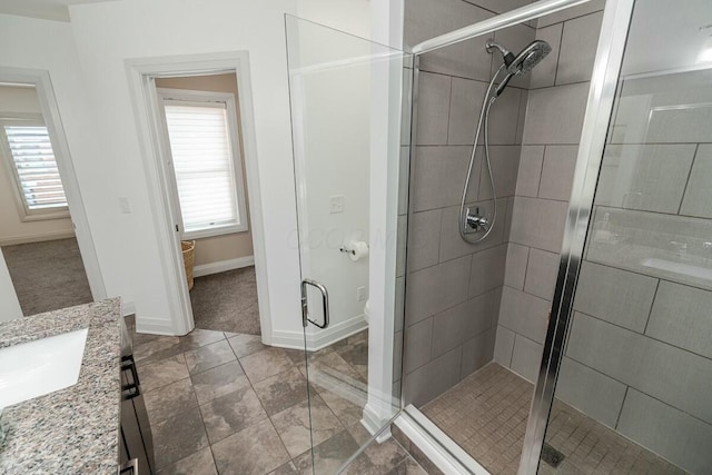 full bathroom with a shower stall, vanity, and baseboards