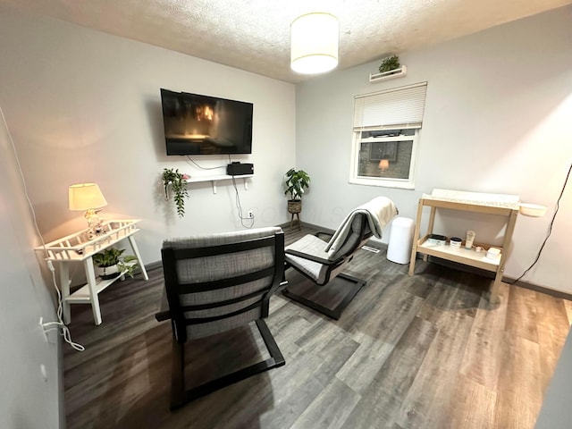 living room with a textured ceiling, wood finished floors, and baseboards