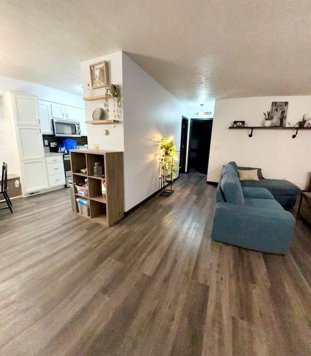 living room featuring baseboards, dark wood finished floors, and a textured ceiling