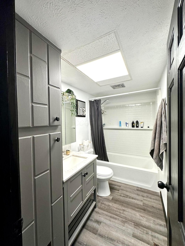 bathroom with toilet, wood finished floors, vanity, visible vents, and shower / tub combo with curtain